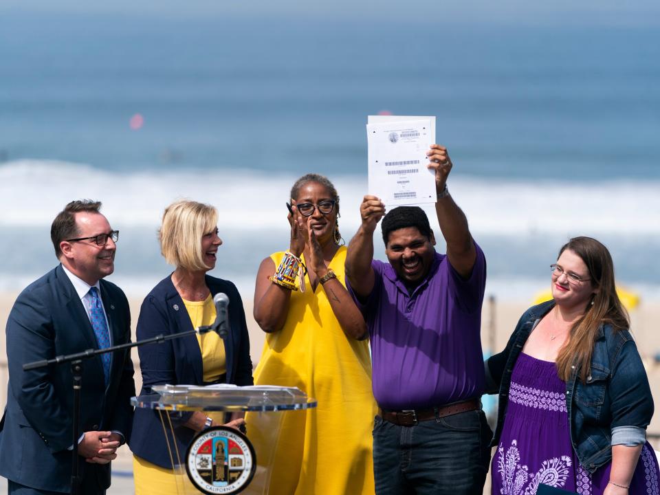 Anthony Bruce, second from right, a great-great grandson of Charles and Willa Bruce, holds up the title deed of the oceanfront property known as Bruce's Beach during a dedication ceremony in Manhattan Beach, Calif., Wednesday, July 20, 2022.