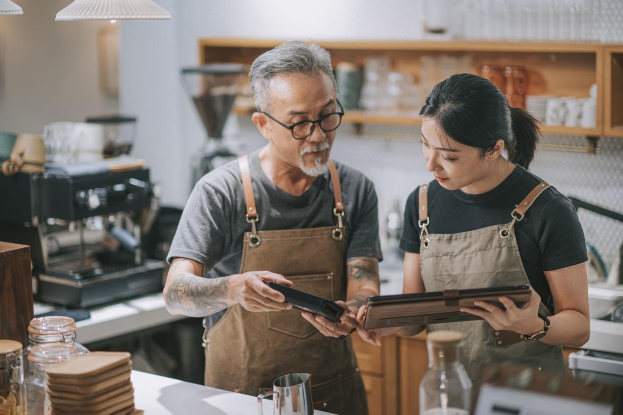 asian chinese senior man owner and daughter using digital tablet at bar counter table