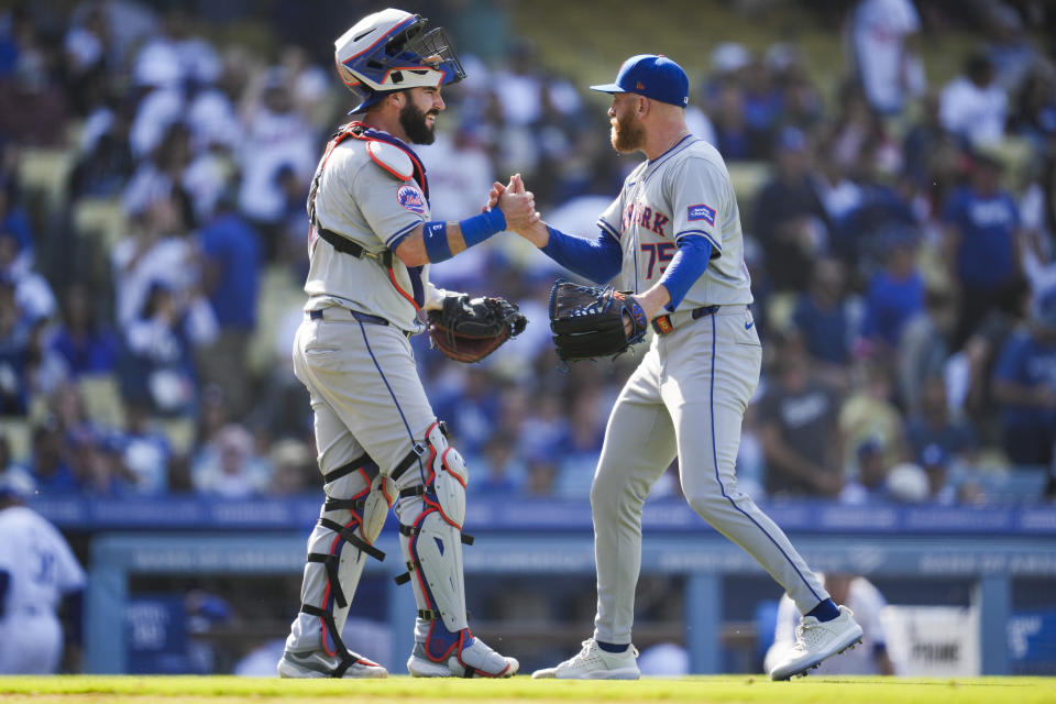 New York Mets catcher Omar Narváez, left, and relief pitcher Reed Garrett (75) celebrate after a 6-4 win over the Los Angeles Dodgers in a baseball game in Los Angeles, Saturday, April 20, 2024. (AP Photo/Ashley Landis)