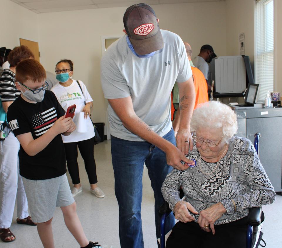 Curtis Litton places an "I voted" sticker on his grandmother Centenarian Mabel Dorothy Duty Cook after she cast her ballot at the Registrar's Office in Chesterfield on Oct. 15, 2020 while Cook's great-grandson Jack Litton records the monumental event.