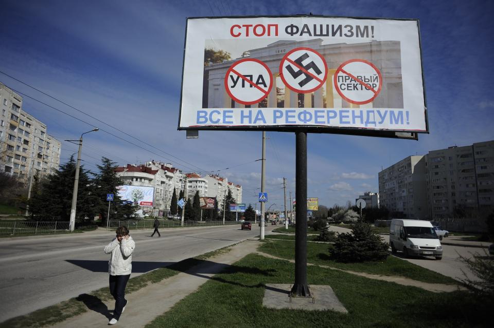 A resident walks by a poster reading "Stop fascism! Everybody to the referendum!" in Sevastopol, Ukraine Thursday, March 13, 2014. Crimea plans to hold a referendum on Sunday that will ask residents if they want the territory to become part of Russia. Ukraine's government and Western nations have denounced the referendum as illegitimate and warned Russia against trying to annex Crimea. (AP Photo/Andrew Lubimov)