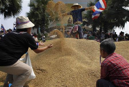 Farmers rearrange a pile of rice after dumping them on the ground during a rally demanding the Yingluck administration resolve delays in payment from the rice pledging scheme, outside a Bank for Agriculture and Agricultural Cooperatives in Bangkok March 11, 2014. REUTERS/Chaiwat Subprasom