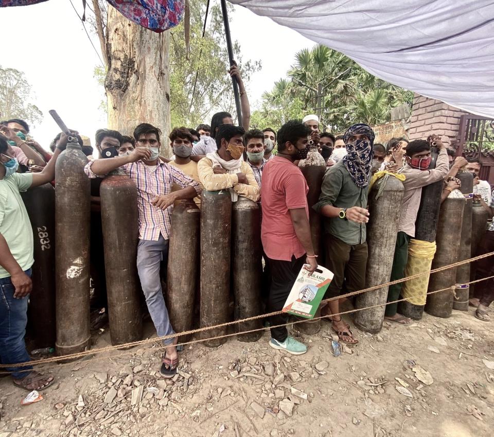 Men stand in line with empty oxygen cylinders