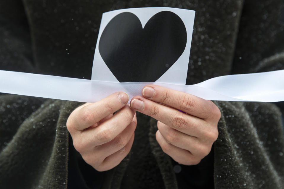 A woman holds an image of heart and a white ribbon as she stands in a line of women during a rally in support of jailed opposition leader Alexei Navalny, and his wife Yulia Navalnaya at Arbat street in Moscow, Russia, Sunday, Feb. 14, 2021. The weekend protests in scores of cities last month over Navalny’s detention represented the largest outpouring of popular discontent in years and appeared to have rattled the Kremlin. (AP Photo/Pavel Golovkin)