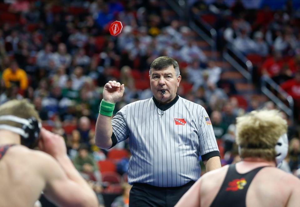 A wrestling official tosses the flip disc into the air in a Class 3A match during the Iowa high school state wrestling tournament at Wells Fargo Arena in Des Moines on Thursday, Feb. 17, 2022.