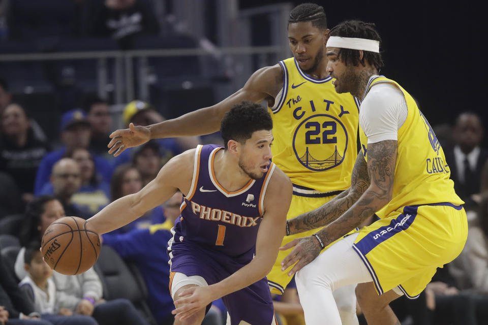 Phoenix Suns guard Devin Booker (1) is is defended by Golden State Warriors forward Glenn Robinson III (22) and center Willie Cauley-Stein during the first half of an NBA basketball game in San Francisco, Friday, Dec. 27, 2019. (AP Photo/Jeff Chiu)
