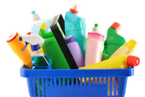 Shopping basket with detergent bottles and chemical cleaning supplies isolated on white