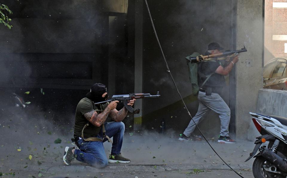 Shiite fighters from Hezbollah and Amal movements take aim with a Kalashnikov assault rifle and a rocket-propelled grenade launcher during clashes in the area of Tayouneh, in the southern suburb of the capital Beirut, on Oct. 14, 2021.