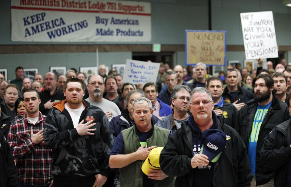 Machinists union members and supporters hold their right hands over their hearts as they recite the Pledge of Allegiance to begin a rally asking members to vote against a proposed contract Thursday, Jan. 2, 2014, in Seattle. National leaders at the International Association of Machinists and Aerospace Workers recently announced a vote on Boeing's proposal despite the objections of local union leaders who had rejected the offer. The local leaders are recommending that members vote "no," in Friday's vote despite Boeing's threat that work on its new 777X airplane will go elsewhere if workers don't take the deal. (AP Photo/Elaine Thompson)