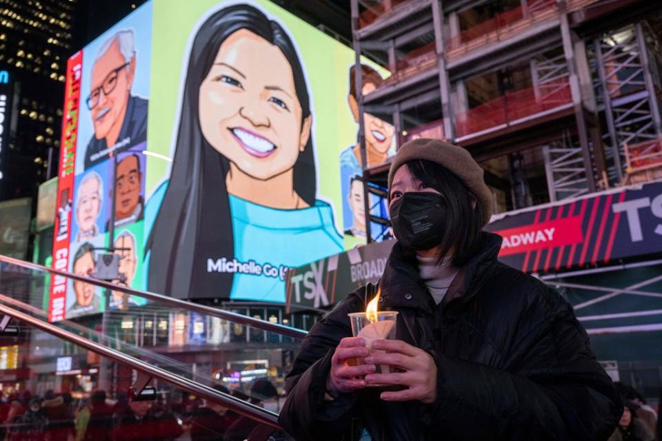A person holds a candle during a vigil, Jan. 18, 2022, in New York's Times Square, in honor of Michelle Alyssa Go, a victim of a subway attack several days earlier.