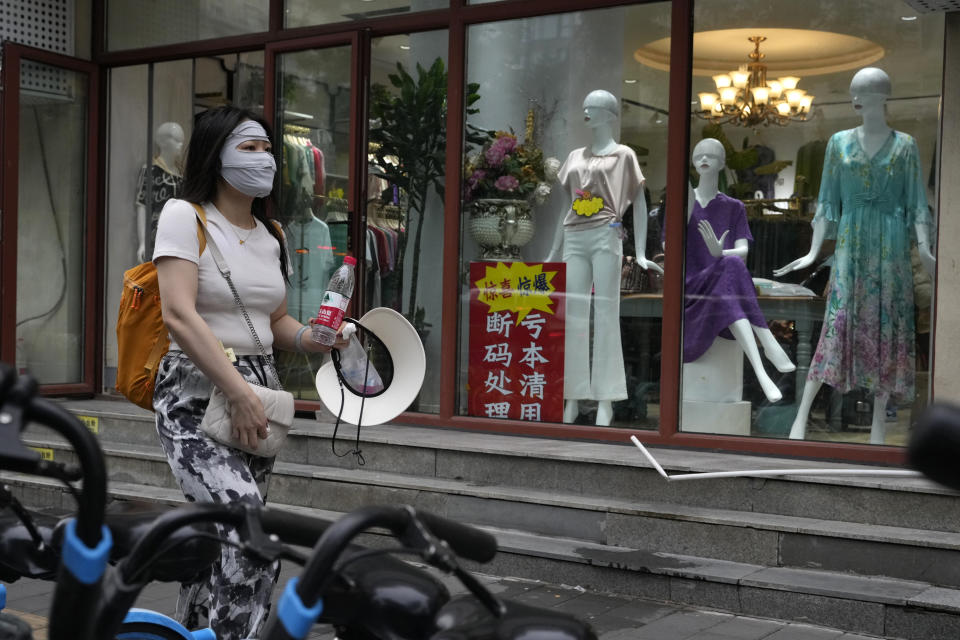 A woman walks past a store with a sign which reads "Clearing at a lost, left-over sizes clearance" at a store in Beijing, Thursday, July 27, 2023. Chinese leader Xi Jinping's government is promising to drag the economy out of a crisis of confidence aggravated by tensions with Washington, wilting exports, job losses and anxiety among foreign companies about an expanded anti-spying law. (AP Photo/Ng Han Guan)