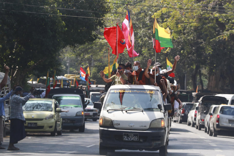 Buddhist religious and military flags are waved by supporters including Buddhist monks onboard a vehicle Monday, Feb. 1, 2021, in Yangon, Myanmar. Myanmar's military has announced it will hold a new election at the end of a one-year state of emergency it declared Monday when it seized control of the country and reportedly detained leader Aung San Suu Kyi. (AP Photo/Thein Zaw)