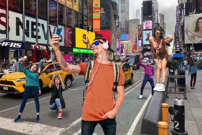 a bunch of poeple taking selfies in Times Square