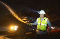 Pacific Gas and Electric employee Sean Ohaire hoses down a telephone pole at the Zogg Fire near Igo, Calif., early Monday, Sep. 28, 2020. (AP Photo/Ethan Swope)