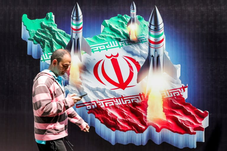 Un hombre pasa frente a un cartel de unos misiles lanzados desde un mapa de Irán con su bandera nacional, el 15 de abril de 2024 en el centro de Teherán (Atta Kenare)