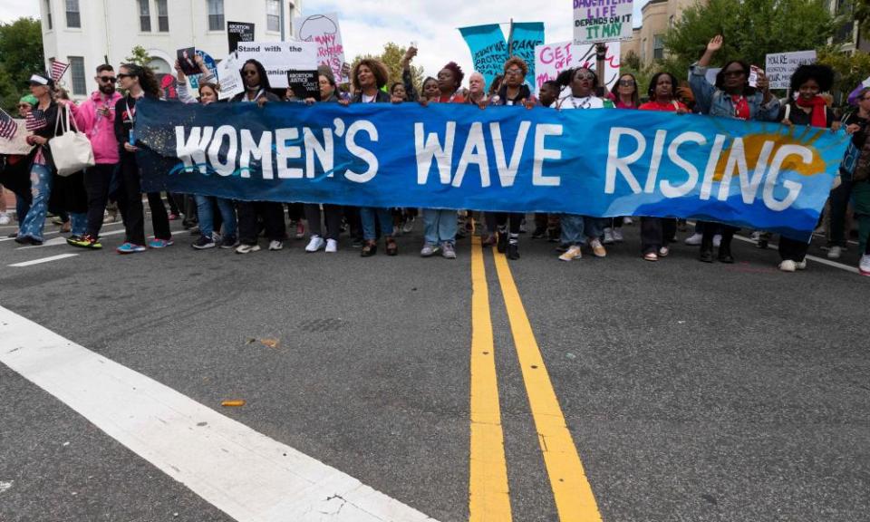 Women marching with a banner reading 'Women's Wave Rising'