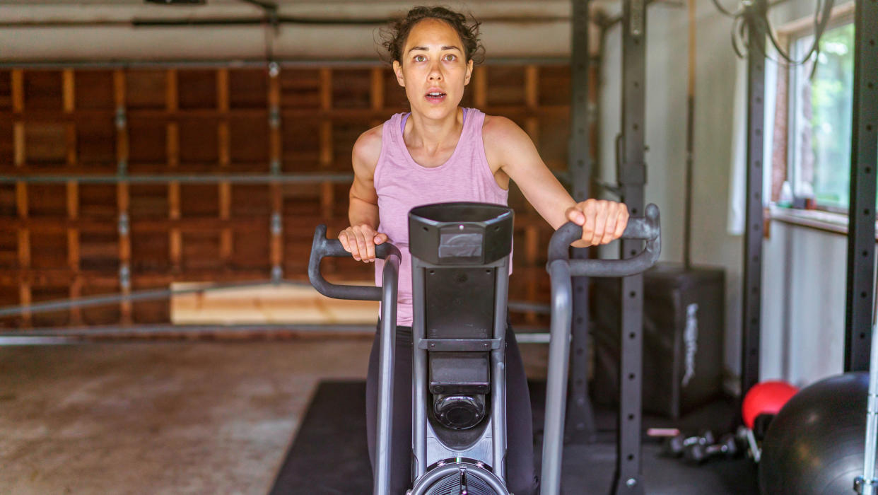  Woman riding air bike in garage. 