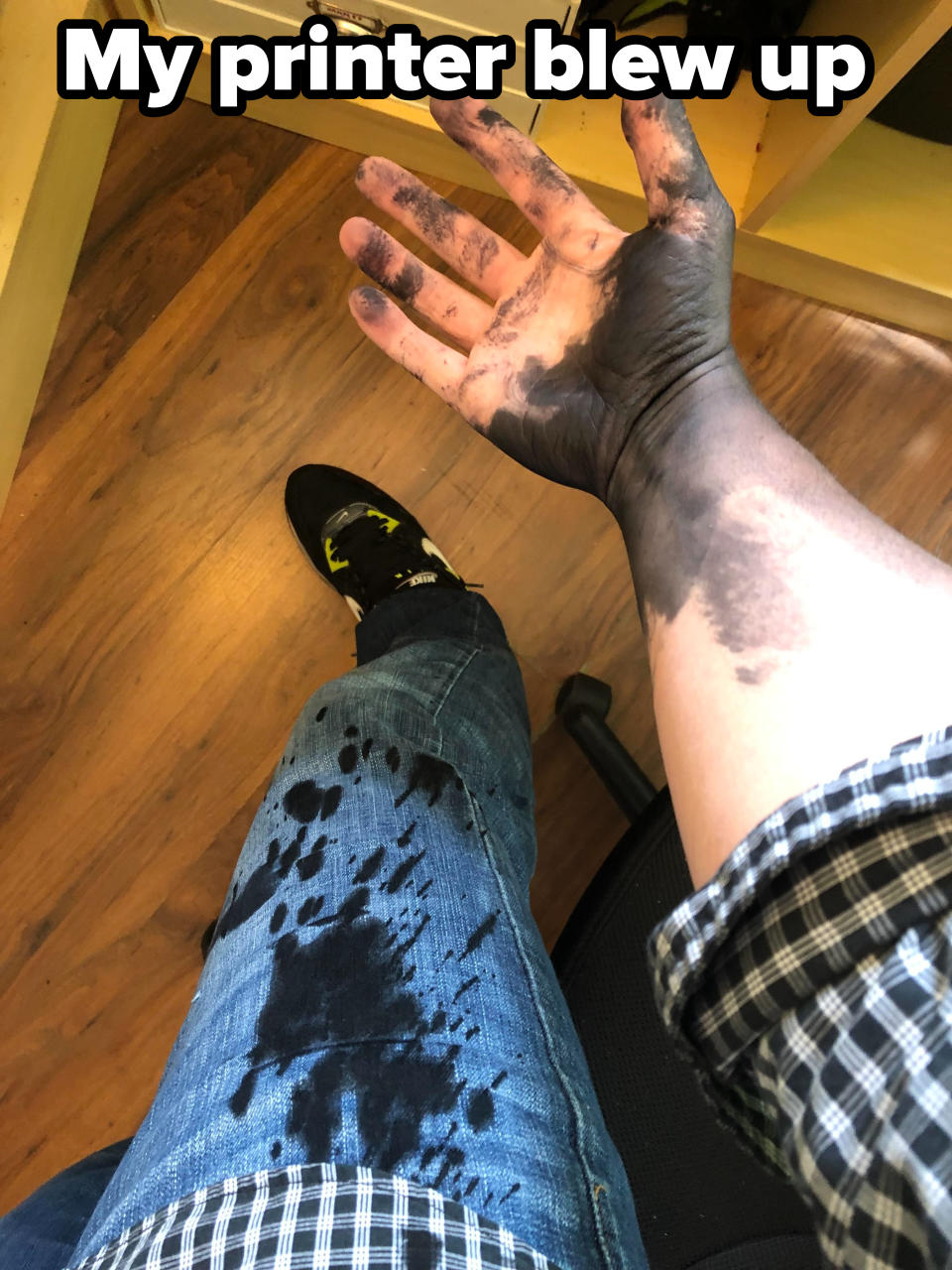 A person with ink-stained hand and blue jeans, sitting indoors