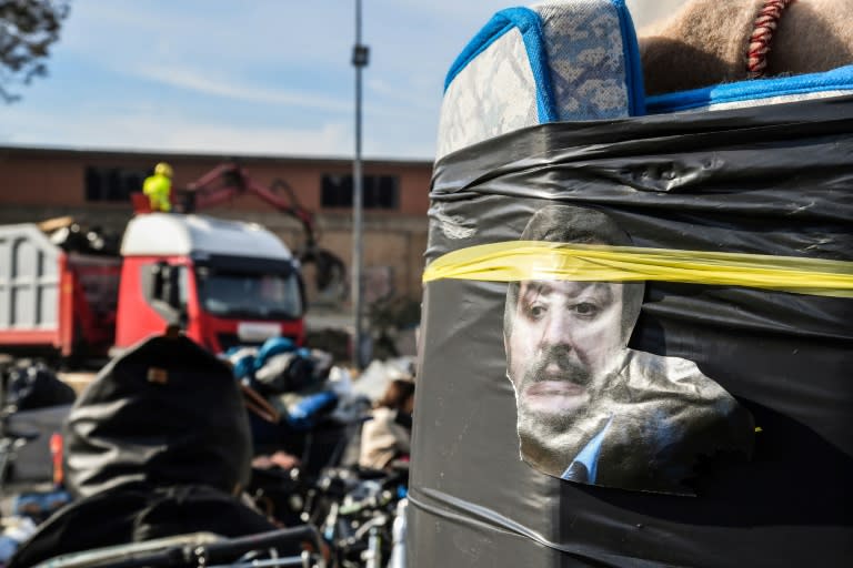 A cutout photo of Italian interior minister Matteo Salvini's head glares from the side of a rolled up mattress as a crane sweeps up discarded belongings at the destruction of a makeshift migrant camp in Rome