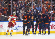 Calgary Flames' Christopher Tanev (8) skates past as the Edmonton Oilers celebrate a goal during the third period of an NHL hockey game Saturday, Oct. 16, 2021, in Edmonton, Alberta. (Jason Franson/The Canadian Press via AP)