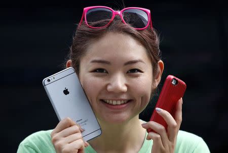 A woman holds a mock iPhone 6 plus (L) and an iPhone 5s as she waits in a line, ahead of the September 19 release of iPhone 6 and iPhone 6 Plus, in front of an Apple Store at Tokyo's Ginza shopping district September 10, 2014. REUTERS/Yuya Shino