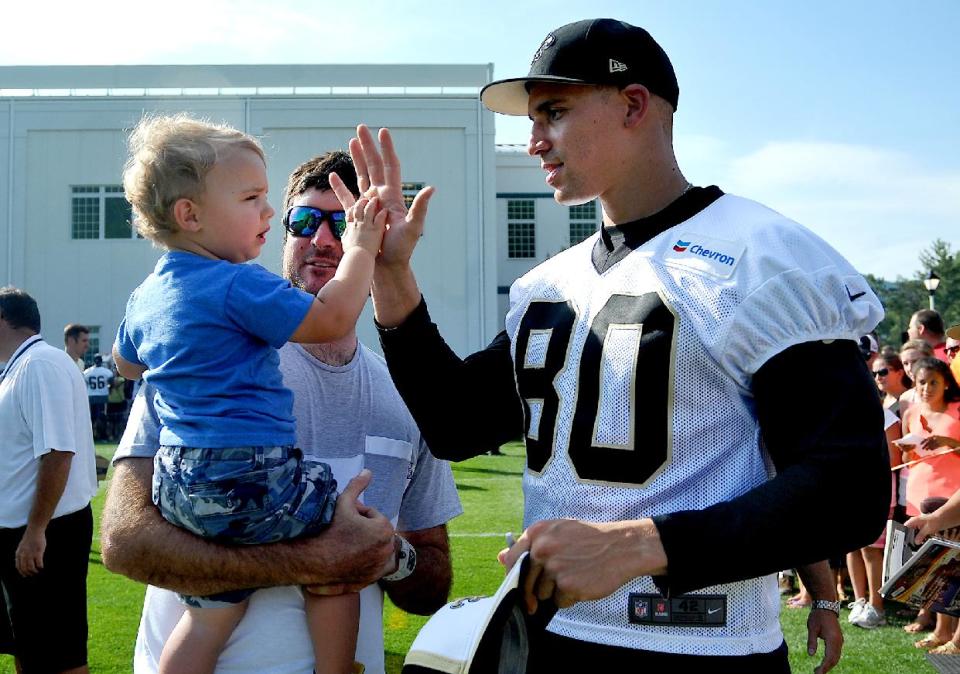 PGA golfer Bubba Watson holds his son Caleb who gives New Orleans Saints tight end Jimmy Graham (80) a high-five during an NFL football training camp in White Sulphur Springs, W.Va., Saturday, July 26, 2014. (AP Photo/Chris Tilley)