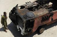 An Israeli soldier inspects a burnt armoured vehicle near the Kerem Shalom border crossing. Egypt's army vowed Monday to "avenge" the killing of 16 troops by gunmen near the Israeli border and President Mohamed Morsi won US backing as he ordered his security forces to take full control of the Sinai