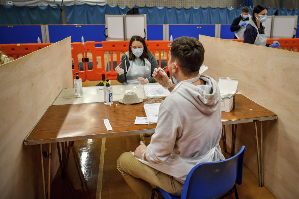 Testing staff members complete lateral flow test swabs, mandatory before opening to the public, at Rhydycar leisure centre in Merthyr Tydfil, Wales, Saturday, Nov. 21, 2020. where mass coronavirus testing begins following a two-week "firebreak" lockdown. (Ben Birchall/PA via AP)