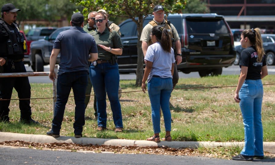 FILE – A law enforcement officer speaks with people outside Uvalde High School after shooting a was reported earlier in the day at Robb Elementary School, Tuesday, May 24, 2022, in Uvalde, Texas. A federal report into the halting and haphazard law enforcement response to a school shooting in Uvalde, Texas, was scheduled to be released Thursday, Jan. 18, 2024, reviving scrutiny of the hundreds of officers who responded to the 2022 massacre but waited more than an hour to confront and kill the gunman. (William Luther/The San Antonio Express-News via AP, File)