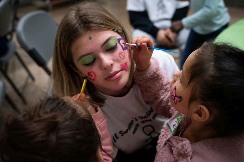 McKenna Weaver, 17, of Oxford, has her face painted by Vayda Hill, 3, left, and older sister Romy Hill, 4, both of Uvalde, during the Survivors United Play Day event at SSGT Willie de Leon Civic Center in Uvalde, Texas on Saturday, Nov. 19, 2022.