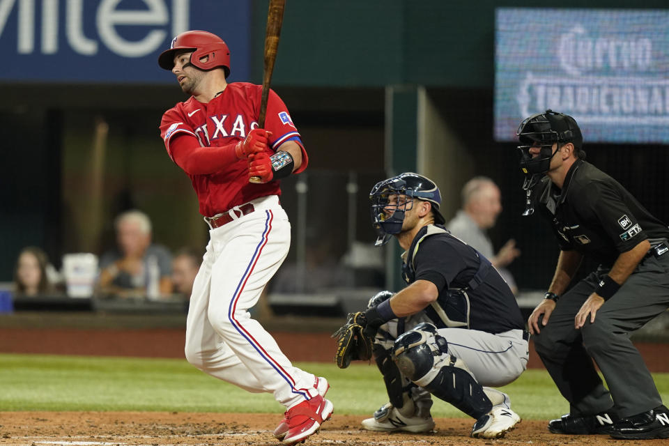 Texas Rangers' Kevin Plawecki, left, swings through after hitting a single in front of Cleveland Guardians catcher Luke Maile, center, and umpire Pat Hoberg, right, during the second inning of a baseball game in Arlington, Texas, Friday, Sept. 23, 2022. Rangers' Adolis Garcia scored from second on the play. (AP Photo/LM Otero)