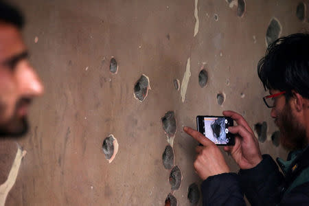 A man uses his mobile phone to take pictures of a bullet-riddled wall of a residential house that was damaged during a gun battle between Zakir Rashid Bhat also known as Zakir Musa, the leader of an al Qaeda affiliated militant group in Kashmir, and Indian security forces on Thursday, in Dadasara village in south Kashmir's Tral May 24, 2019. REUTERS/Danish Ismail