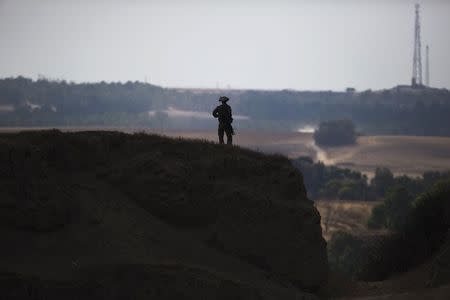 An Israeli soldier stands guard on a hill outside central Gaza Strip July 19, 2014. REUTERS/Amir Cohen