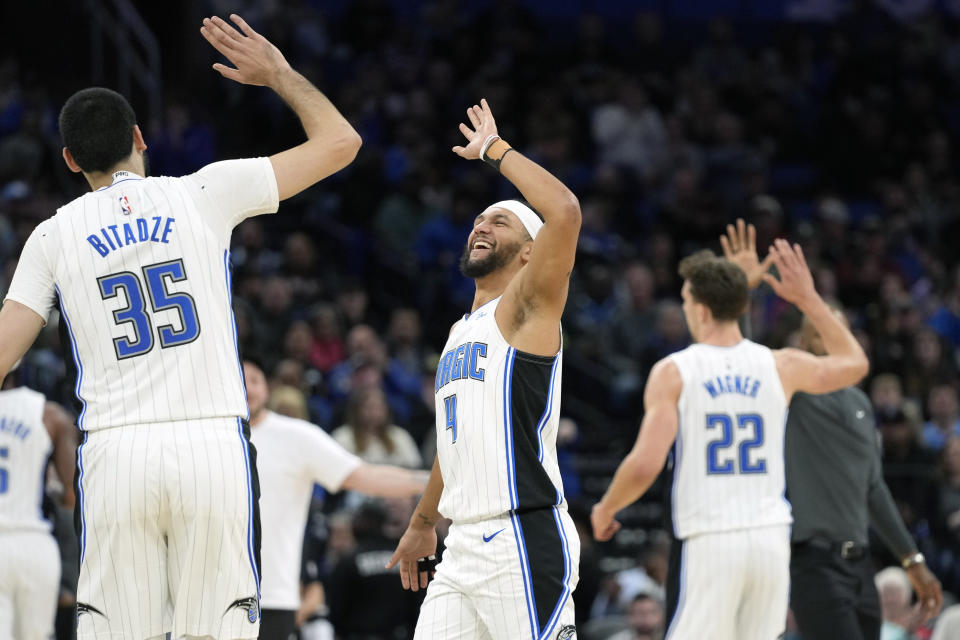 Orlando Magic center Goga Bitadze (35), guard Jalen Suggs (4), forward Franz Wagner (22) and head coach Jamahl Mosley, back right, trade high-fives during a timeout after a big play against the New York Knicks in the second half of an NBA basketball game, Friday, Dec. 29, 2023, in Orlando, Fla. (AP Photo/John Raoux)