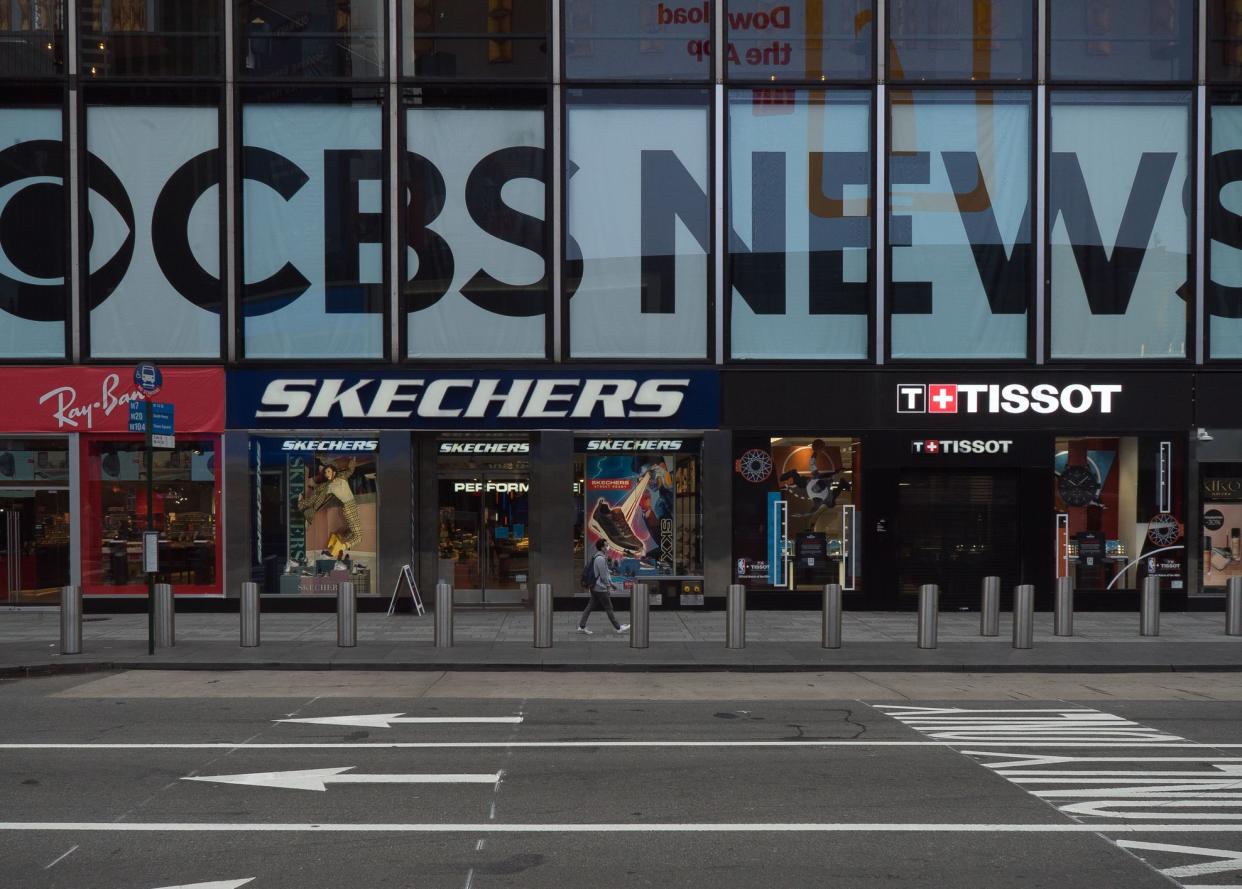 Manhattan, New York. October 22, 2020. A man wearing a mask walks in front of CBS News studios in Times Square.