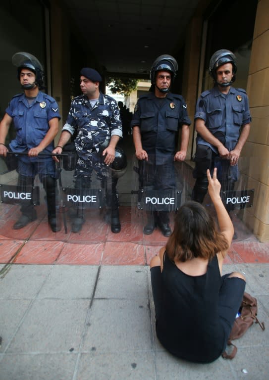 A Lebanese activist flashes the sign for victory in front of riot police outside the environment ministry in downtown Beirut on September 1, 2015