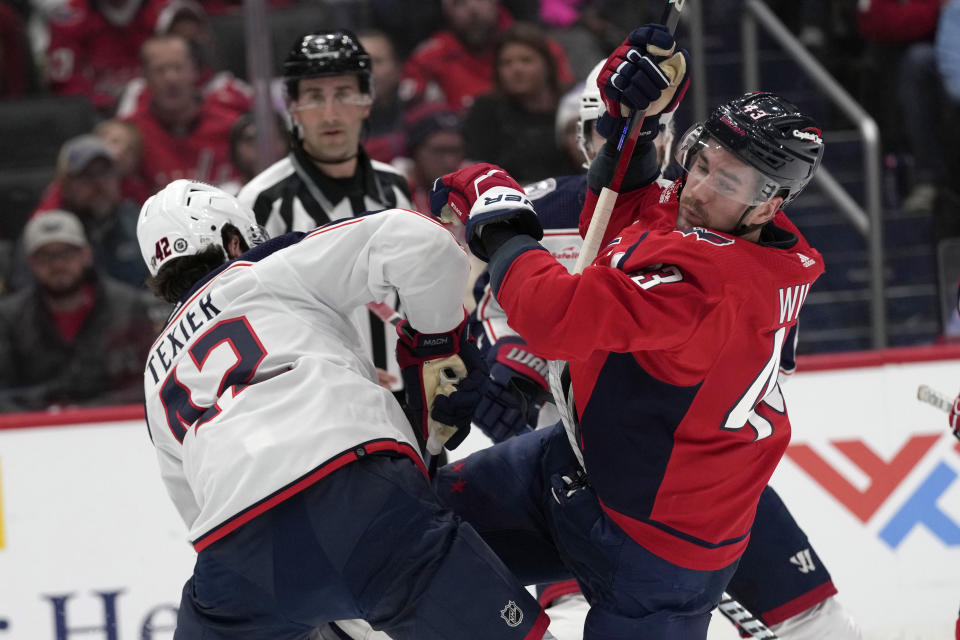 Washington Capitals right wing Tom Wilson (43) right, gets caught up with Columbus Blue Jackets center Alexandre Texier (42) during the first period of an NHL hockey game in Washington, Saturday, Nov. 18, 2023. (AP Photo/Susan Walsh)