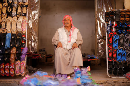 A shop vendor sits in front of his shop at Aleppo's Sheikh Maqsoud neighbourhood Syria July 15, 2017. REUTERS/Omar Sanadiki