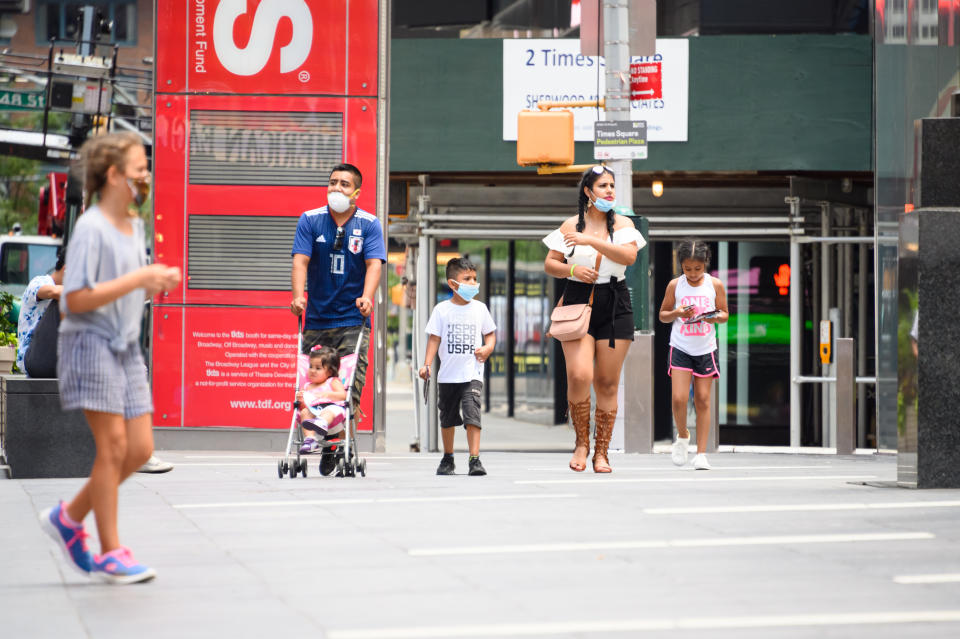 NEW YORK, NEW YORK - JULY 12: Family members wear face masks in Times Square as New York City moves into Phase 3 of re-opening following restrictions imposed to curb the coronavirus pandemic on July 12, 2020. Phase 3 permits the reopening of nail and tanning salons, tattoo parlors, spas and massages, dog runs and numerous other outdoor activities. Phase 3 is the third of four-phased stages designated by the state. (Photo by Noam Galai/Getty Images)