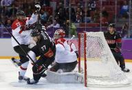 Canada's Jeff Carter is upended by Austria's Thomas Pock in front of Austria's goalie Bernhard Starkbaum during the first period of their men's preliminary round ice hockey game at the 2014 Sochi Winter Olympics, February 14, 2014. REUTERS/Gary Hershorn (RUSSIA - Tags: TPX IMAGES OF THE DAY SPORT ICE HOCKEY OLYMPICS)