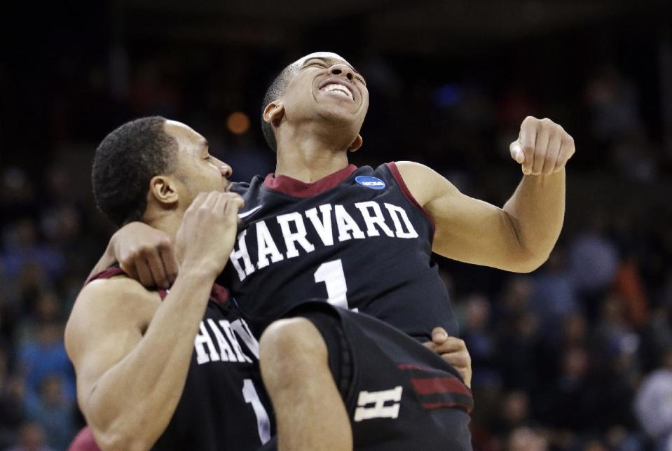 Harvard's Siyani Chambers, right, leaps into the arms of teammate Brandyn Curry after the team beat Cincinnati in the second round of the NCAA college basketball tournament in Spokane, Wash., Thursday, March 20, 2014. Harvard won 61-57. (AP Photo/Elaine Thompson)