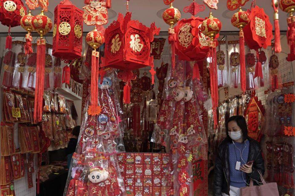 A woman wearing a face mask among Chinese New Year decorations in Hong Kong. The deadly outbreak comes as travel begins for the holiday.