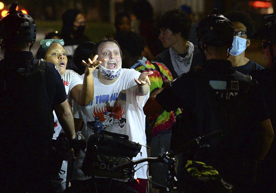 Two protesters express their opinions to Charlotte Mecklenburg Police bike officers at the intersection of South Caldwell Street and Stonewall Street in uptown Charlotte, N.C., on Friday, Aug. 21, 2020. (Jeff Siner/The Charlotte Observer via AP)