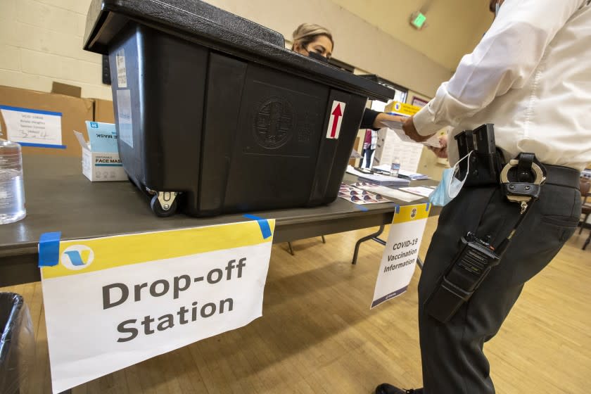 Boyle Heights, CA - September 14,2021: A LAPD officer, right, drops off ballots for the gubernatorial recall election at the Boyle Heights Senior Center on Tuesday, Sept. 14, 2021 in Boyle Heights, CA. (Brian van der Brug / Los Angeles Times)