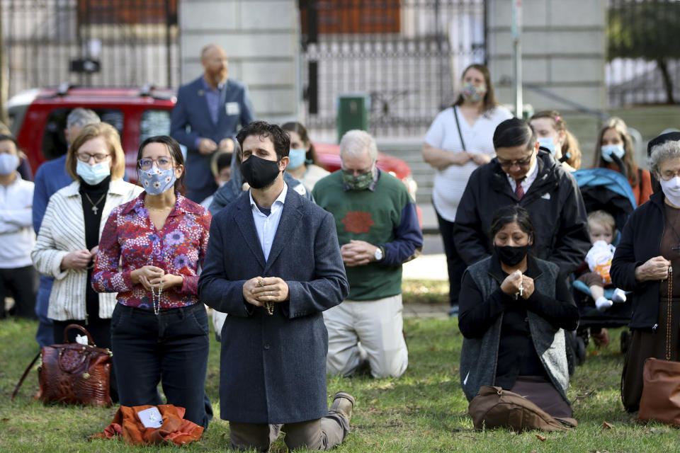 The faithful kneel to pray a rosary in the North Park Blocks during a rosary and exorcism for peace and justice in the city led by Archbishop Alexander Sample on Oct. 17, 2020, in Portland, Ore. In popular culture, exorcism often serves as a plot device in chilling films about demonic possession. Recently, two Roman Catholic archbishops showed a different face of exorcism. They performed the rite in well-attended outdoor ceremonies to drive out any evil spirits lingering after acrimonious protests. In Portland, Oregon, Archbishop Alexander Sample led a procession of more than 200 people to a city park, then conducted an exorcism rite. The event followed more than four months of racial-justice protests in Portland. (Ed Langlois/Catholic Sentinel via AP)