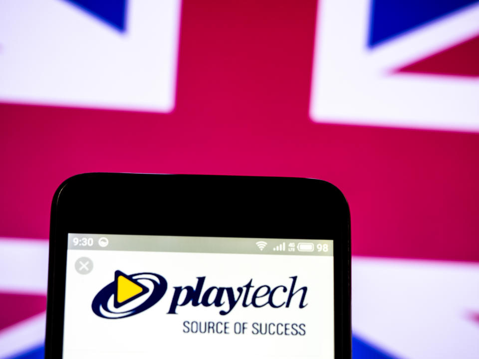 The Playtech PLC logo seen displayed on a smartphone with the Union Jack flag in the background. Source: Getty Images