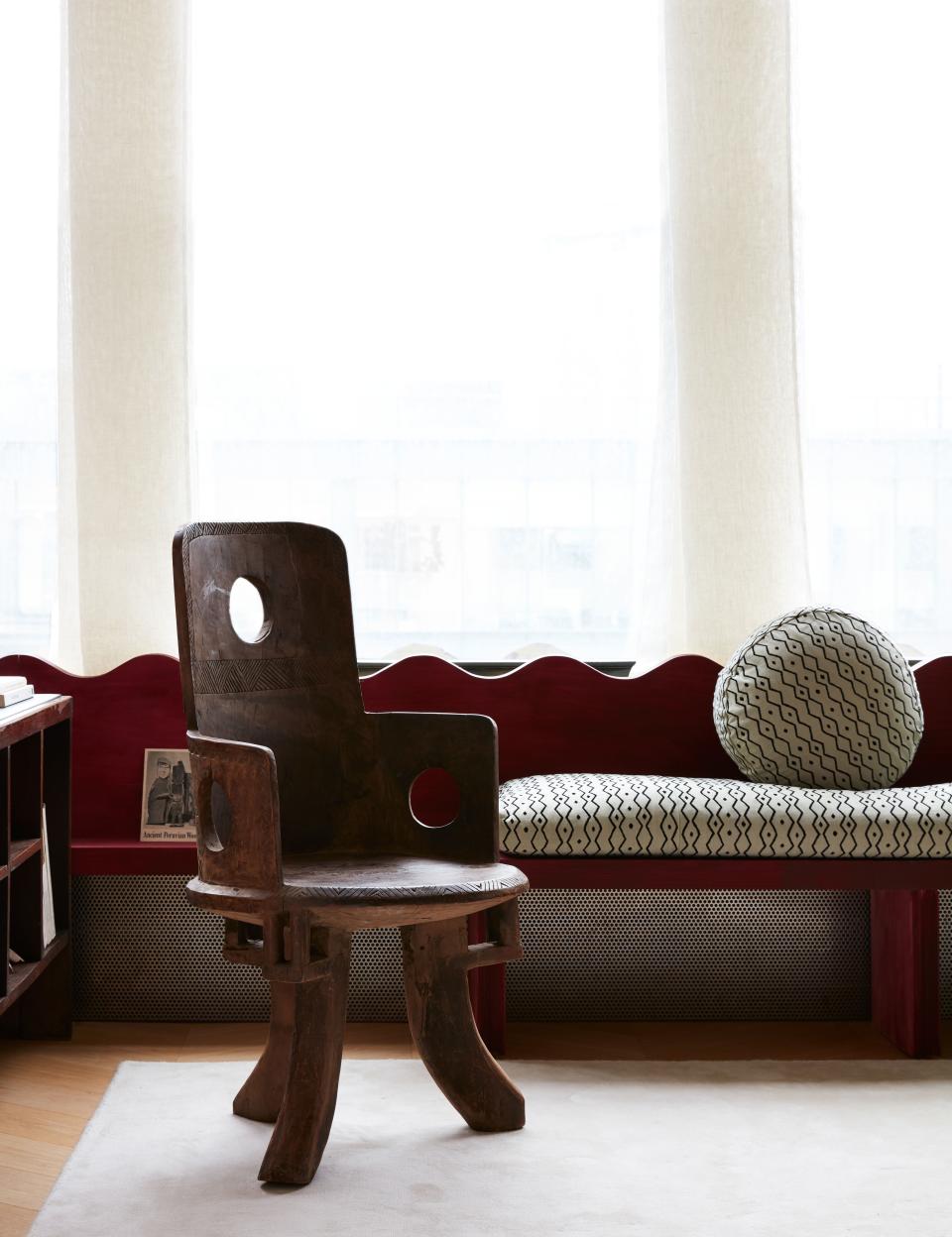 In the living room, Valle designed a low wood screen along the window wall that turns into a window seat. The wood is stained a rich red; the fabric on the cushions is from Le Manach.