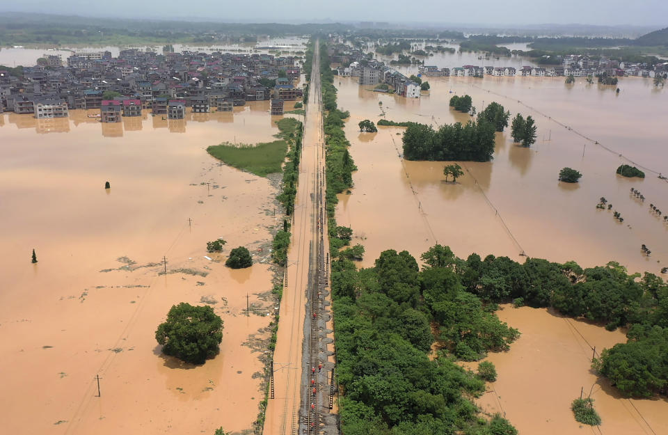 Workers gather along a section of flooded railway in Shangrao in central China's Jiangxi province, Tuesday, June 21, 2022. Major flooding has forced the evacuation of tens of thousands of people in southern China, with more rain expected. (Chinatopix via AP)