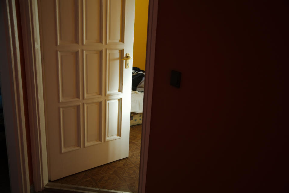 Partially open white door leading to a room with a visible bed, suggesting privacy or rest