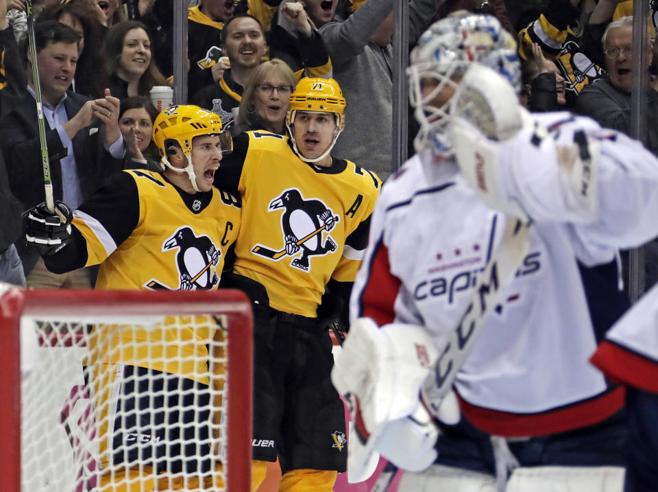 Pittsburgh Penguins' Sidney Crosby (87) celebrates his first of two second period goals with Evgeni Malkin (71) as Washington Capitals goaltender Braden Holtby, right, collects himself during an NHL hockey game in Pittsburgh, Tuesday, March 12, 2019. (AP Photo/Gene J. Puskar)